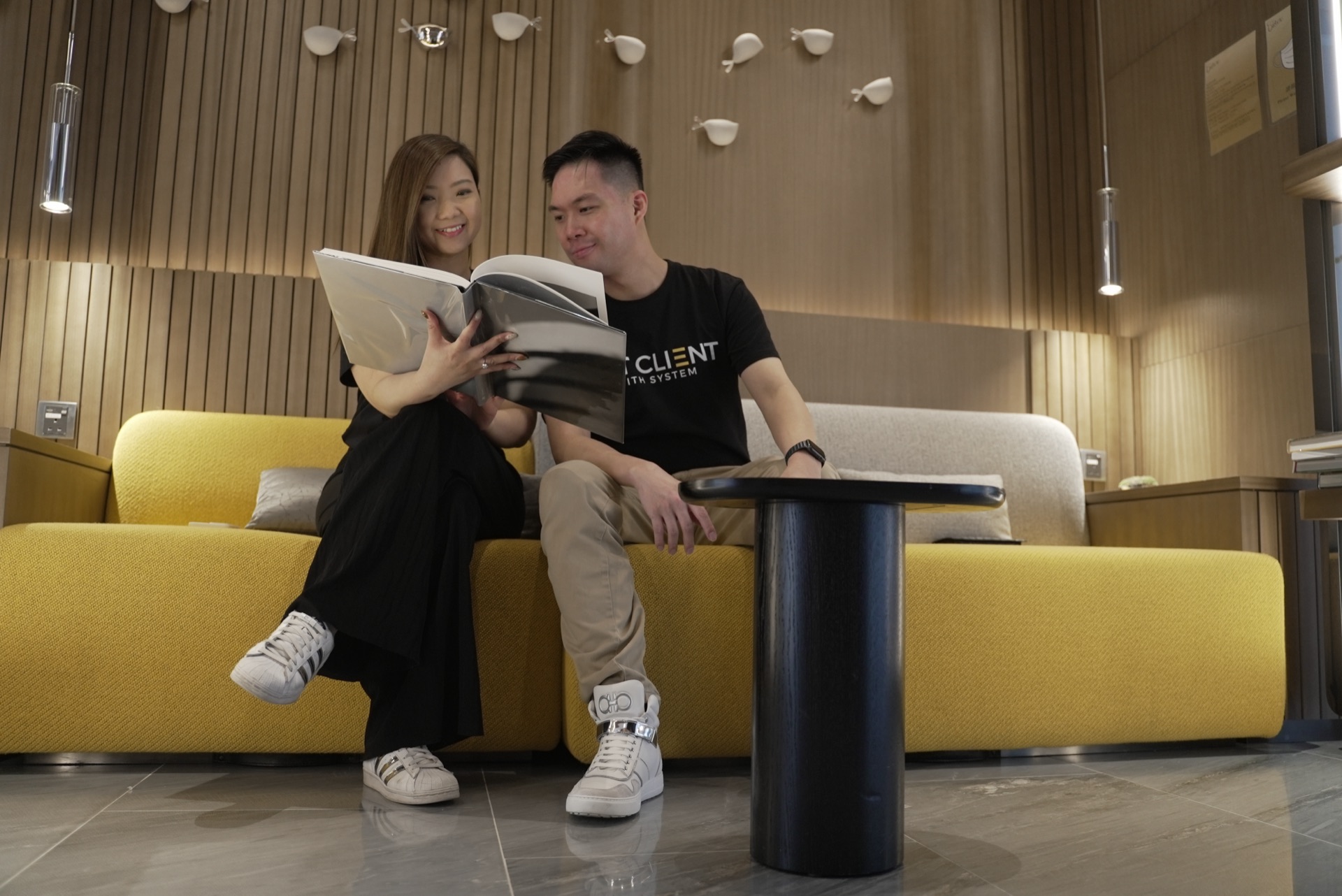 Nic Leung 與 April Lo 坐在黃色梳化上翻閱書本