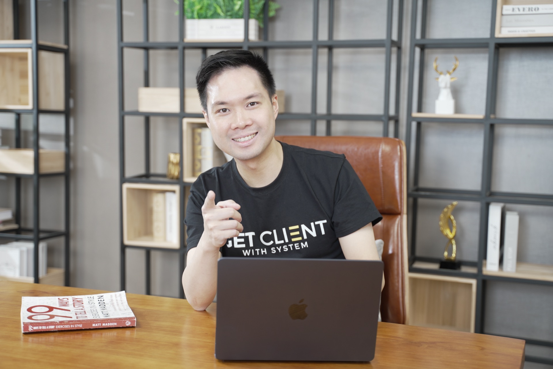 Nic Leung 坐在辦公桌前，手指鏡頭